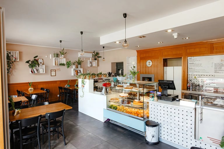 Bright, modern bakery interior with wooden accents, display cases, counter seating, and dining area