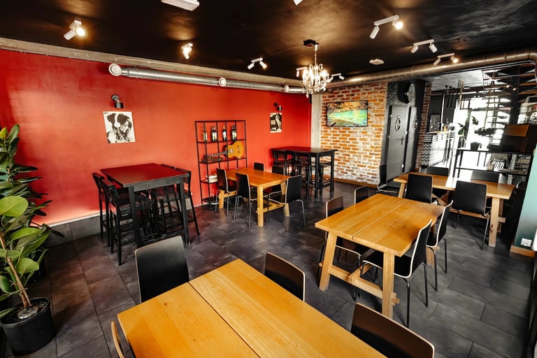 Modern eclectic cafe or restaurant interior with red accent wall, wooden tables, black chairs, brick details, and mixed vintage furnishings